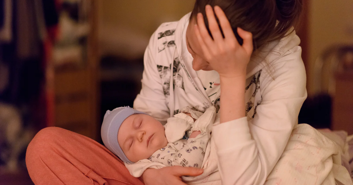 Exhausted new mom cradling baby during late-night feed